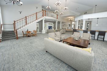 A living room with a grey couch and a staircase